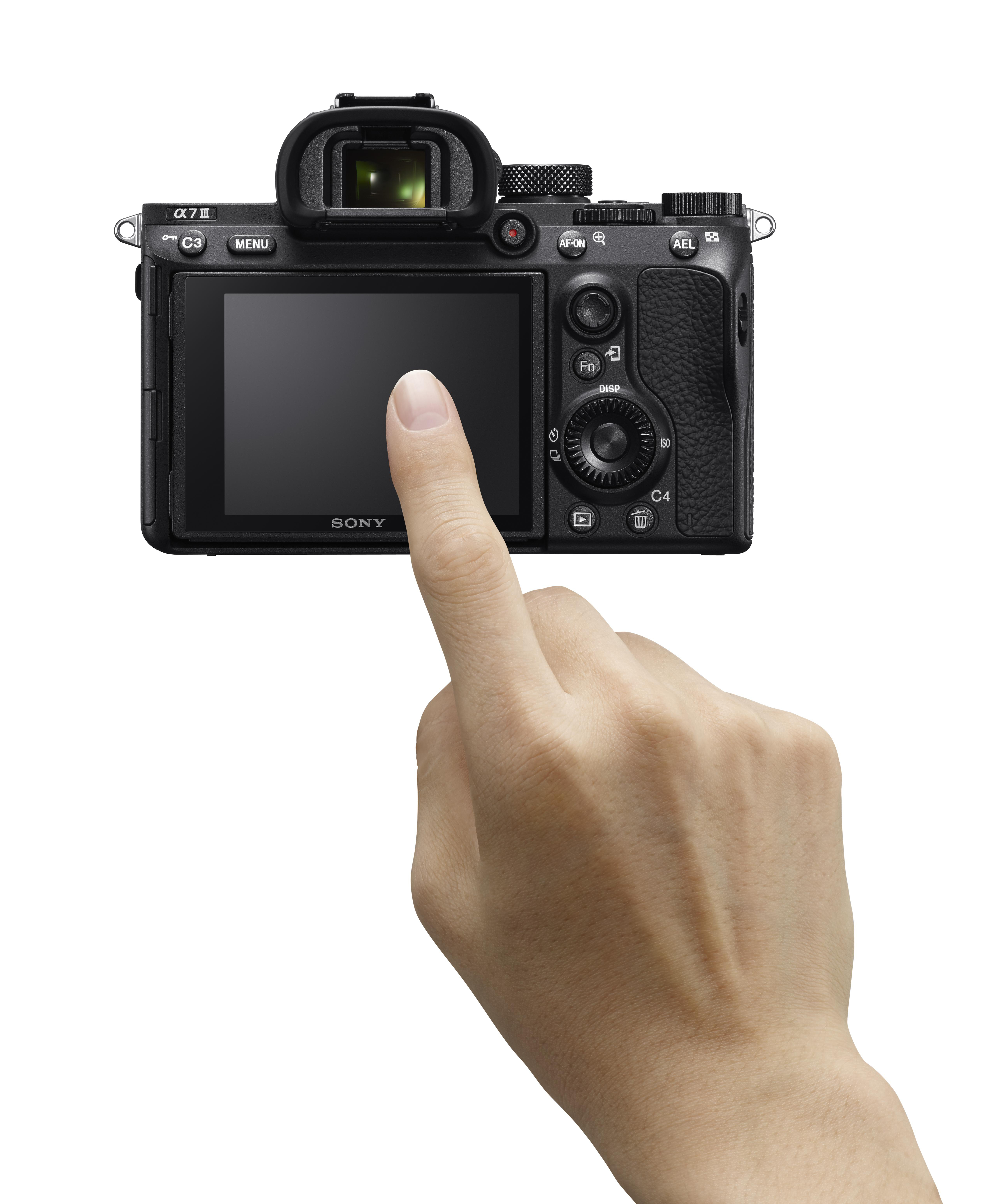 Eine Hand berührt den Bildschirm einer Sony-Kamera. Die Kamera ist schwarz.