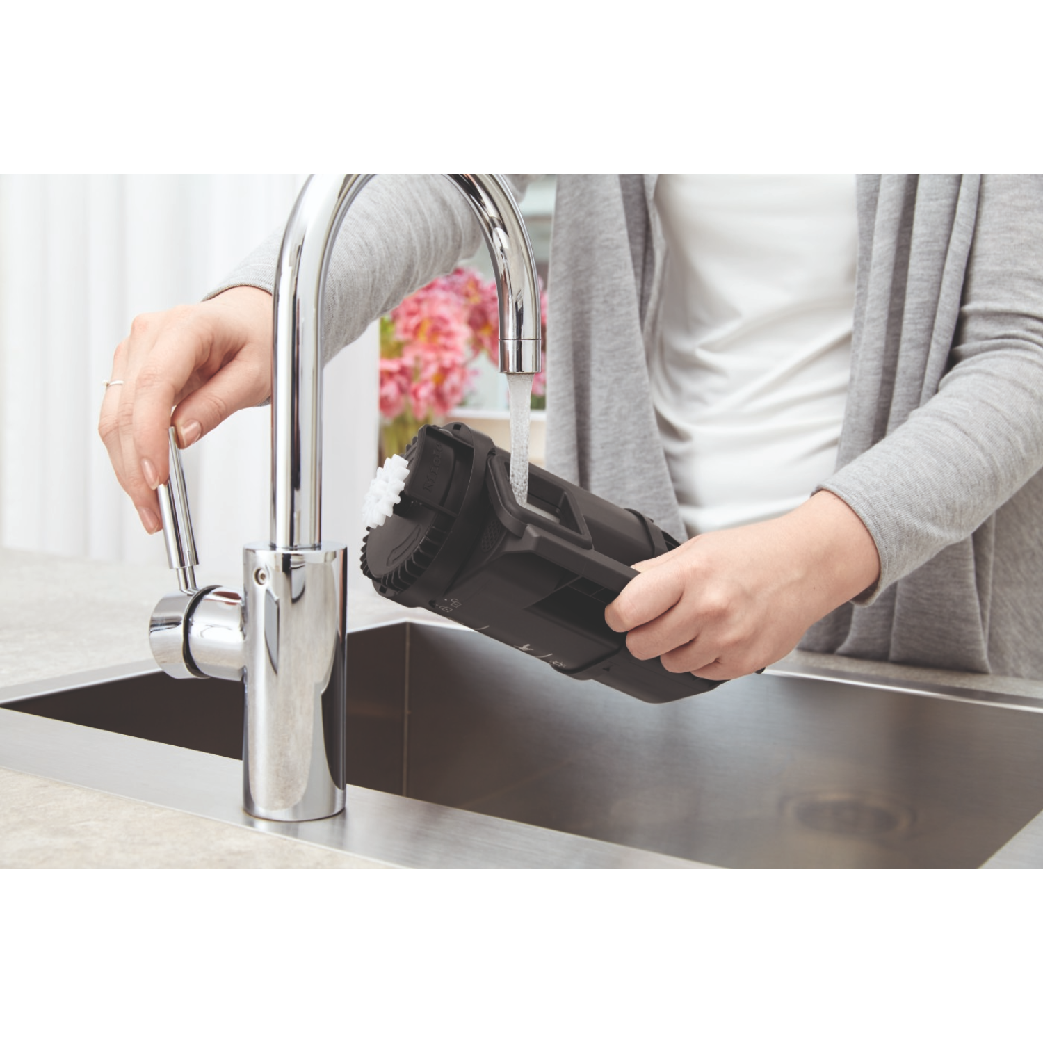 Person filling a black water filter under a faucet in a sink.