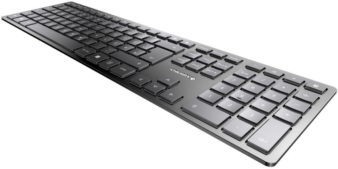 Eine schwarze CHERRY-Tastatur mit vielen Tasten. Sie liegt auf einer weißen Oberfläche und ist leicht nach oben geneigt.