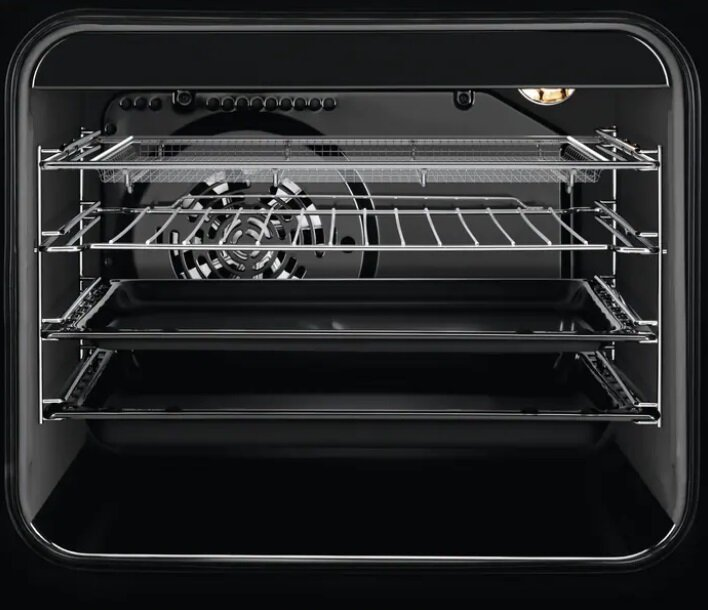 Otwarty wnętrze piekarnika z wieloma rusztami, wentylatorem i ciemną, odblaskową powierzchnią.