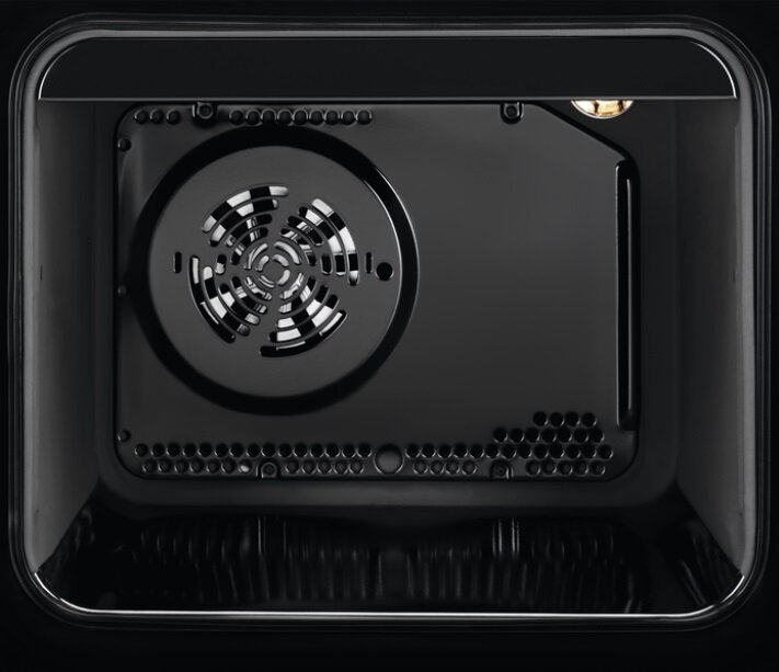 Wnętrze czarnego piekarnika z widocznym wentylatorem i otworami wentylacyjnymi.