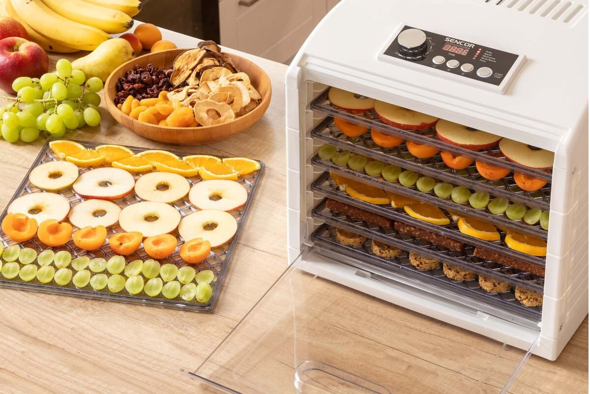 Suszarka do żywności z tacami owoców i warzyw. Suszona żywność i świeże produkty w pobliżu.