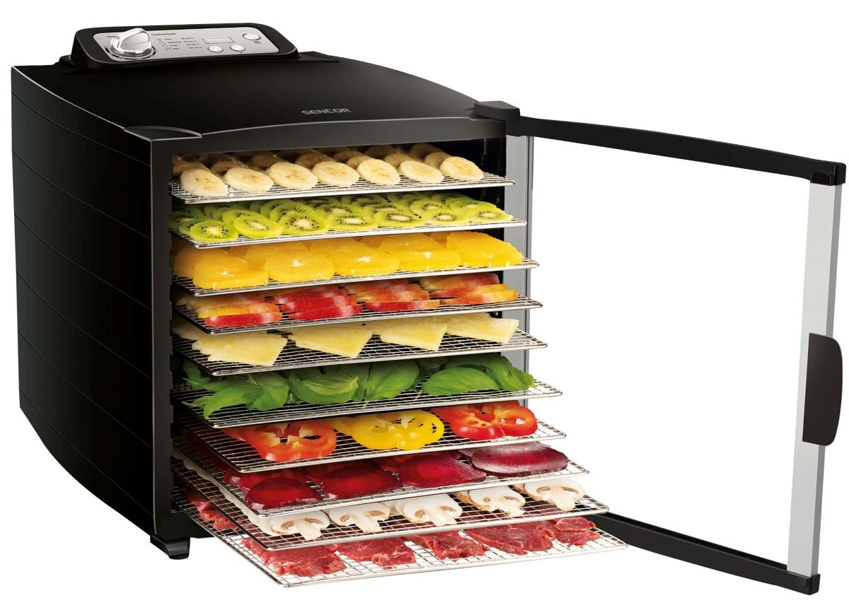 Czarny dehydrator żywności z otwartymi drzwiami, tacki wypełnione owocami i warzywami.