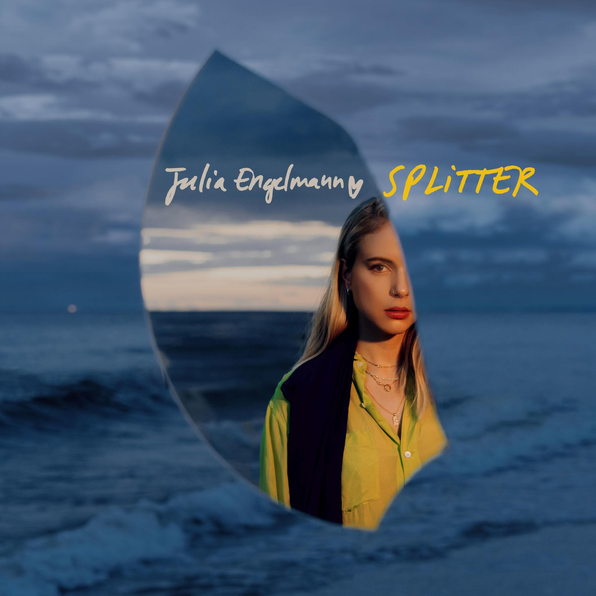 Frau vor Spiegel mit Titel 'Splitter'. Der Hintergrund zeigt Meer und bewölkten Himmel.