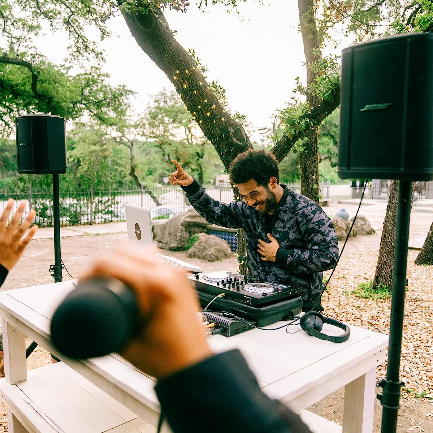 Un DJ a una festa all'aperto, sorridente alla telecamera.