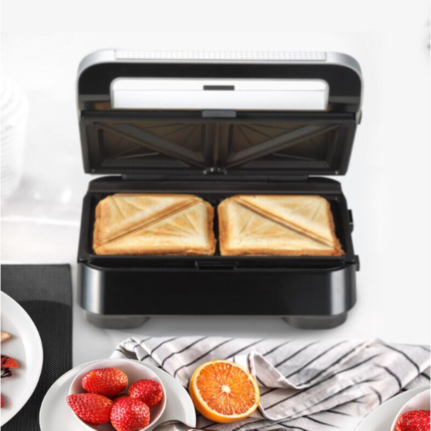 A sandwich maker open, with two toasted sandwiches inside.