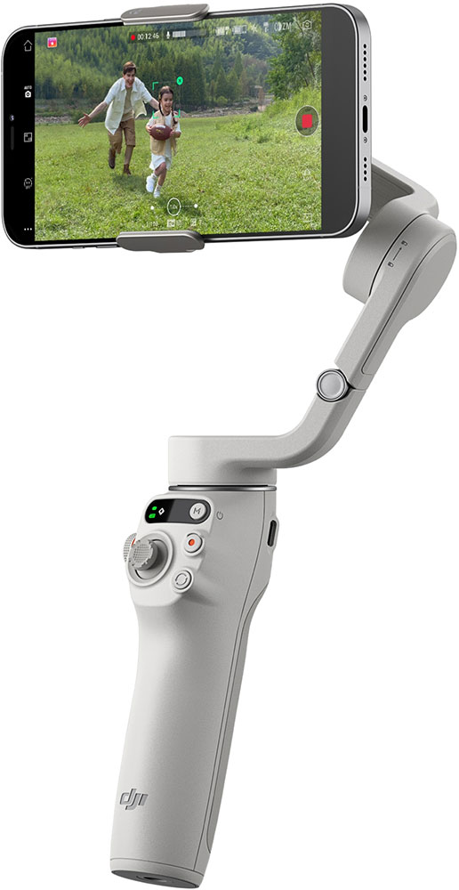 Een handheld gimbal met een telefoon met een video van een man en kind die over gras rennen.
