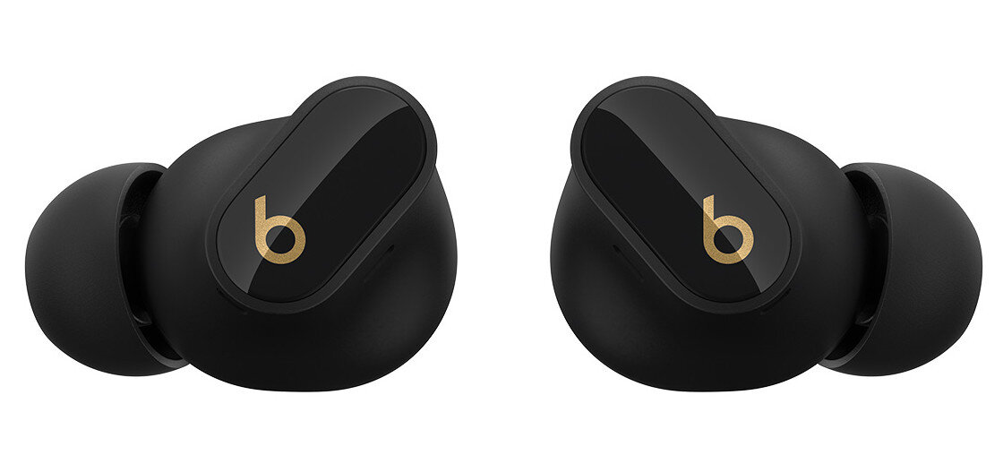 Para czarnych słuchawek Beats ze złotymi logotypami 'b', zbliżenie na białym tle.
