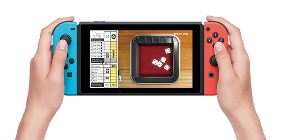 Mains tenant une Nintendo Switch avec un jeu de dés à l'écran.