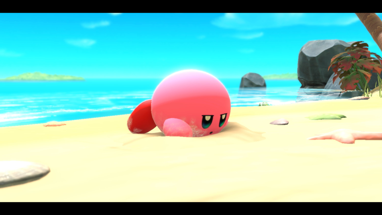 Een roze Kirby-personage is gedeeltelijk begraven in het zand op een strand.
