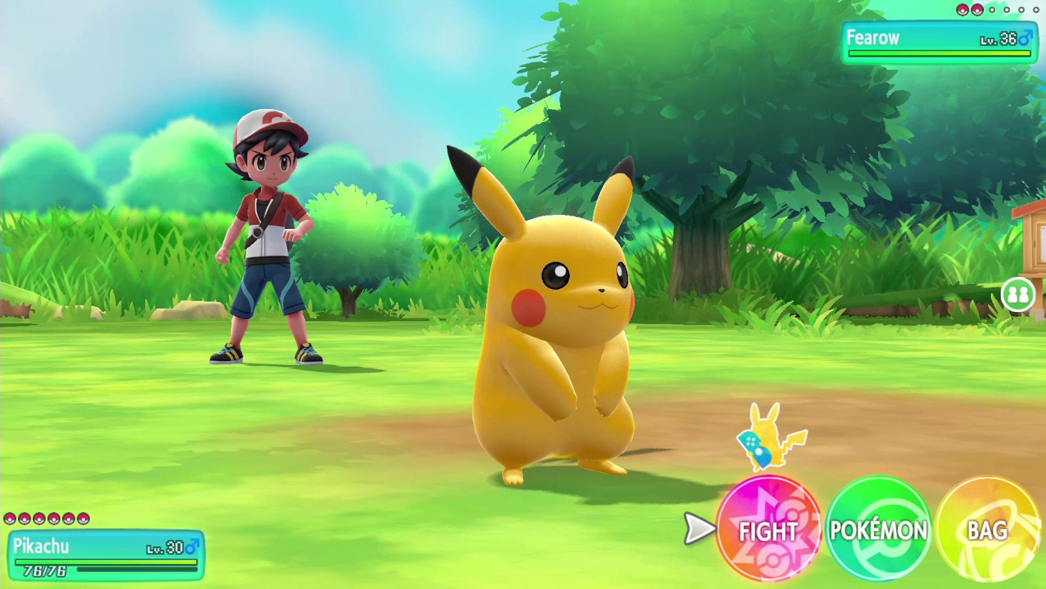 Pikachu staat naar voren gericht. Een jongen in een rood shirt en hoed staat op de achtergrond op groen gras.