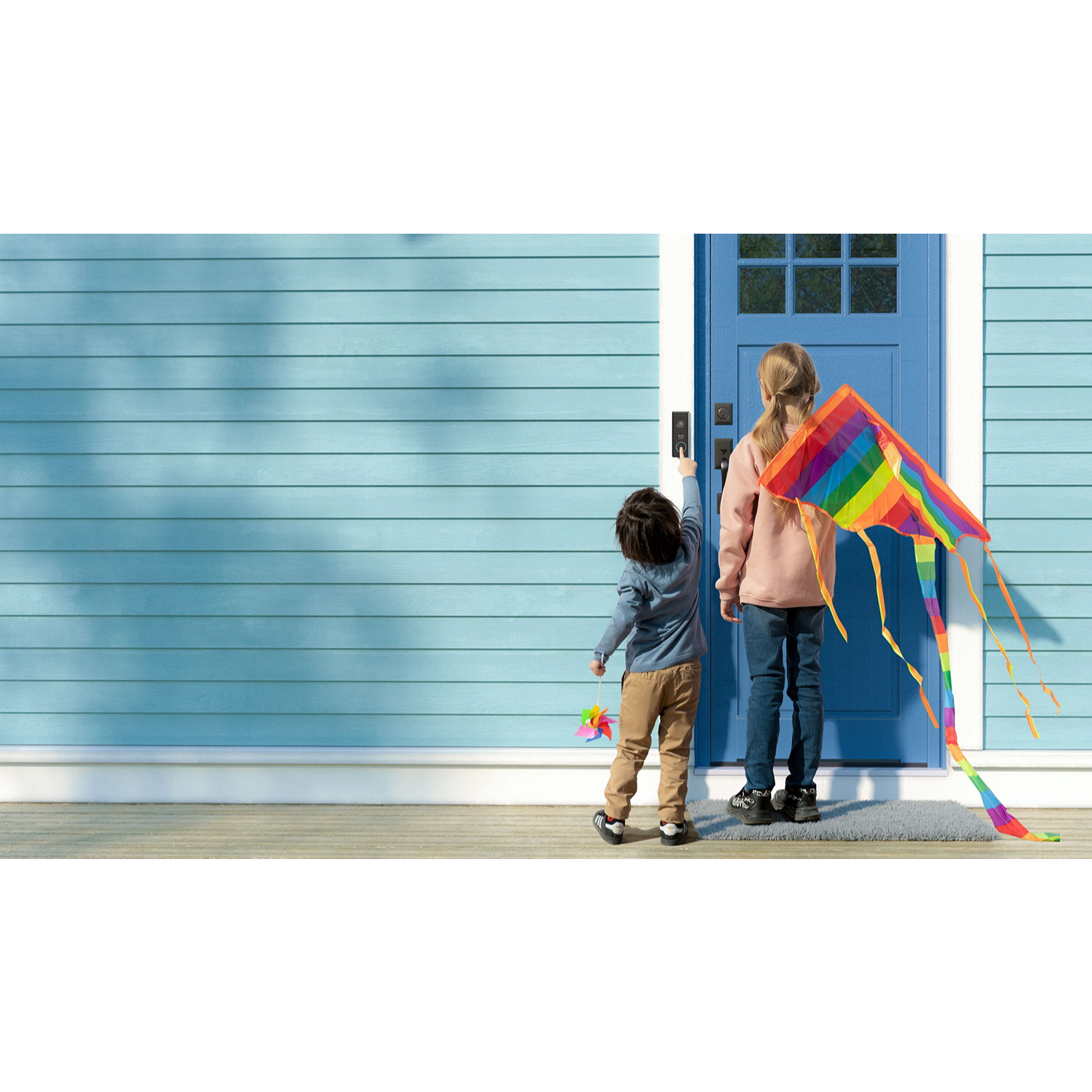 Two children near a blue door with a kite.