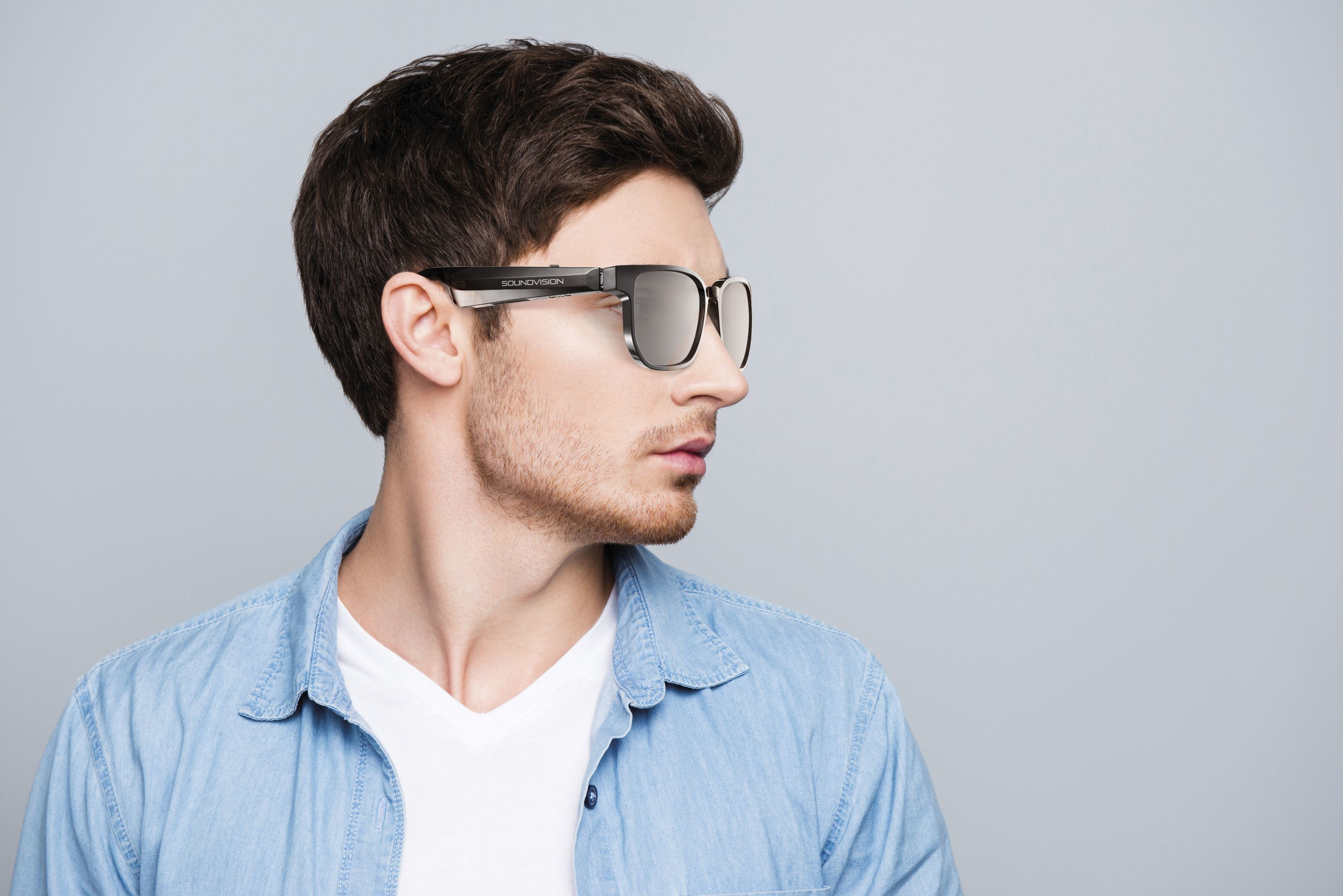 Un homme portant des lunettes Soundvision regardant sur le côté. Il a les cheveux courts et une barbe.