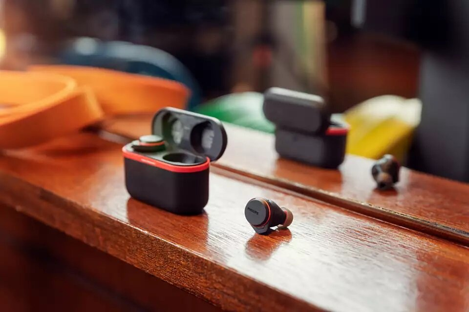 Słuchawki douszne z etui ładującym na drewnie. Czarne i czerwone akcenty.