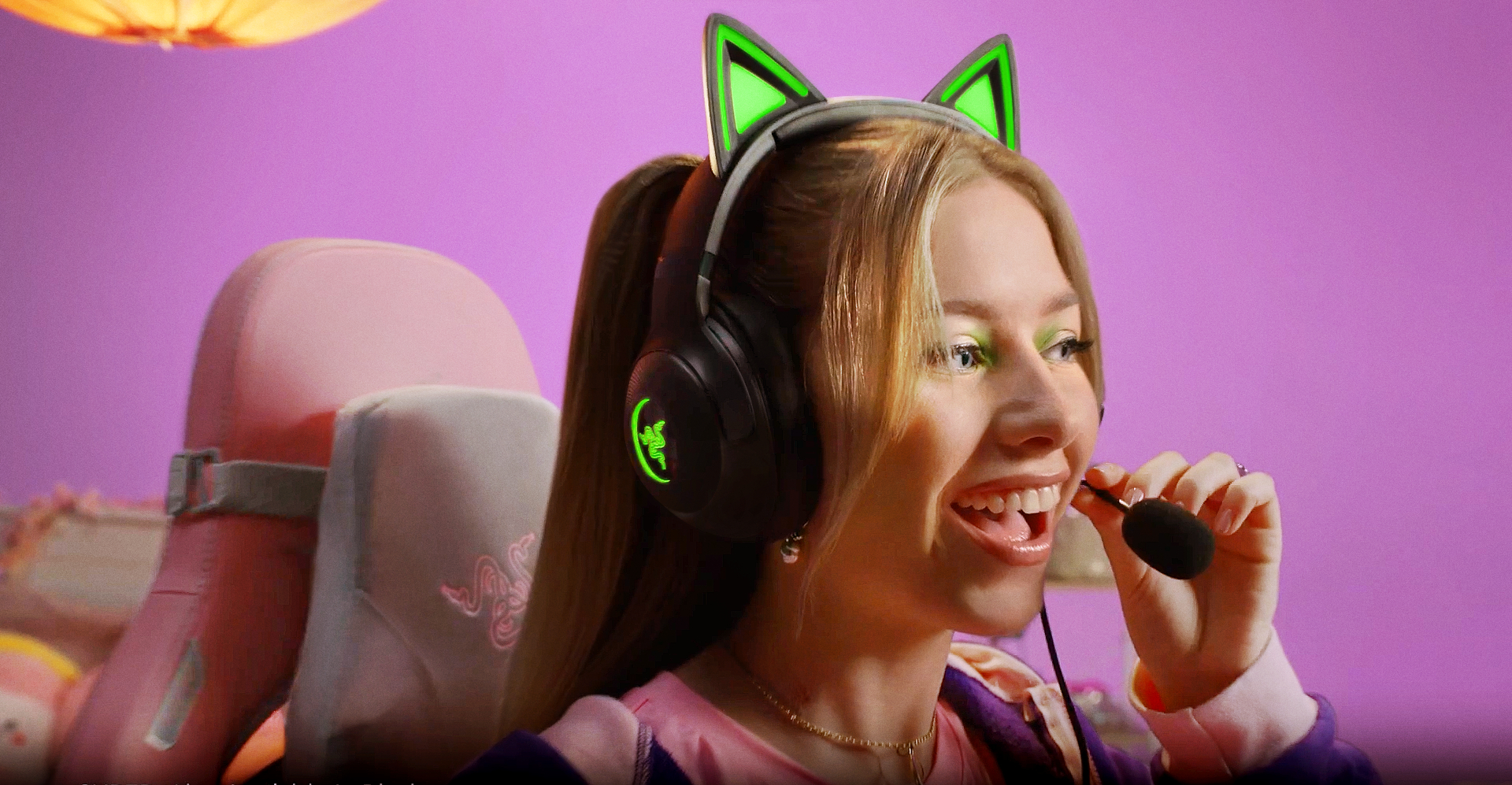 Junge Frau mit Katzenohren-Headset, lächelt und spricht in ein Mikrofon.
