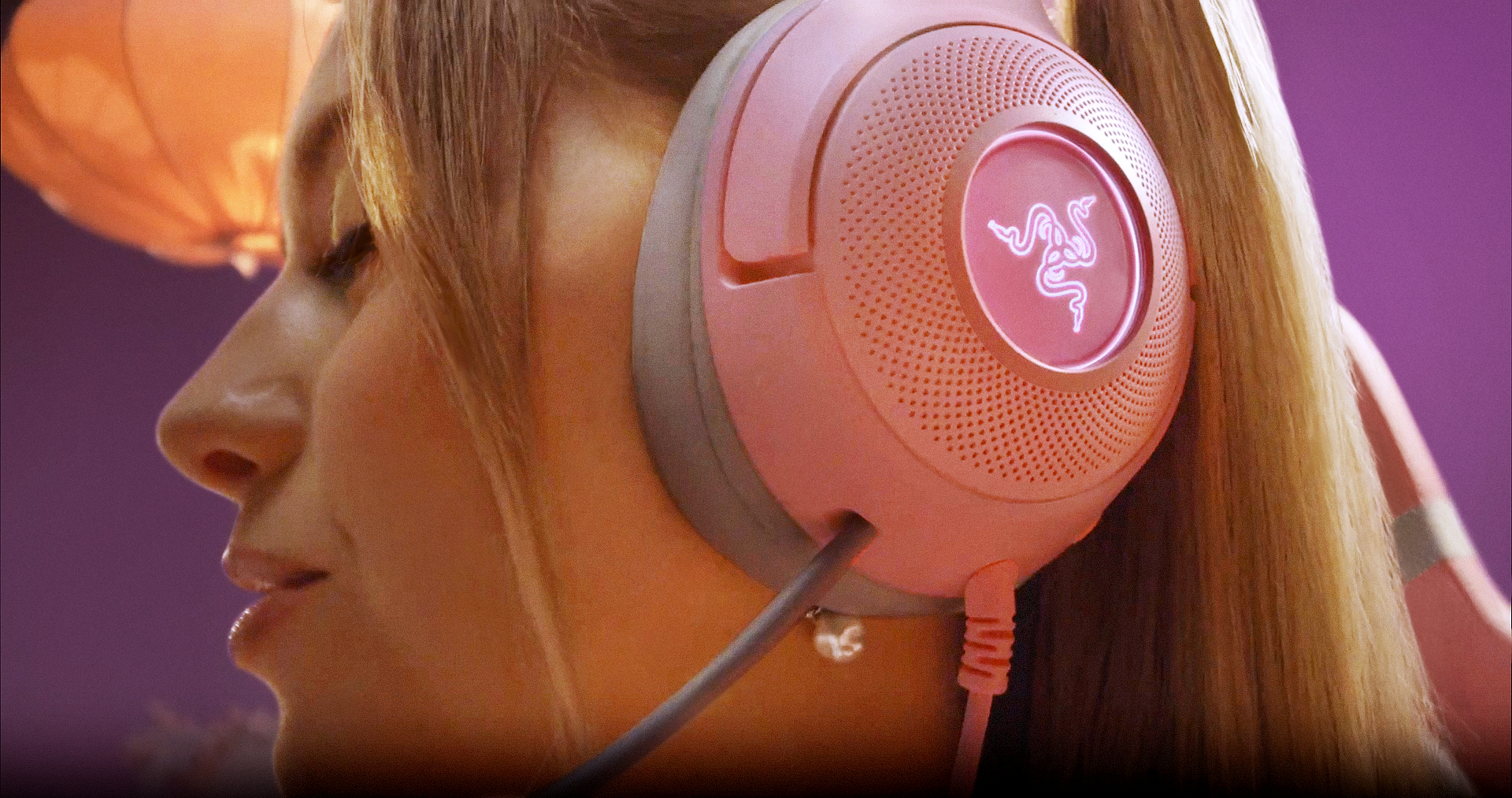 Eine Frau mit rosa Kopfhörern, Nahaufnahme ihres Gesichts. Das Razer-Logo ist sichtbar.