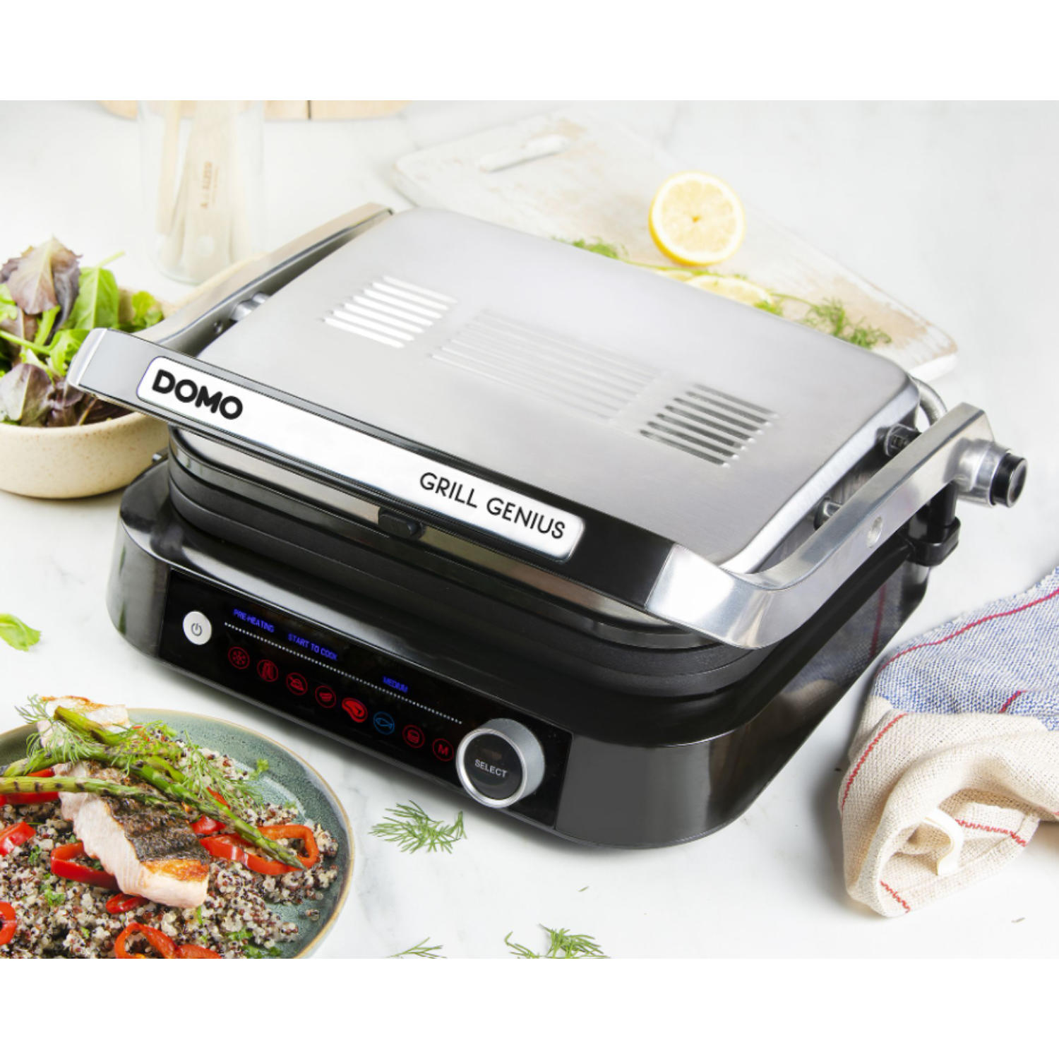 Domo Grill Genius on a marble surface. Grilled food and side salad are on the left. White background.