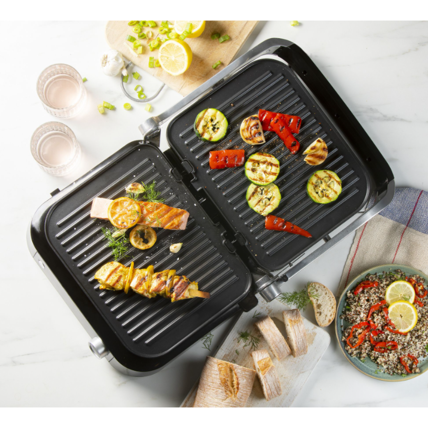 A grill with grilled salmon, vegetables, and other food items on a marble surface.