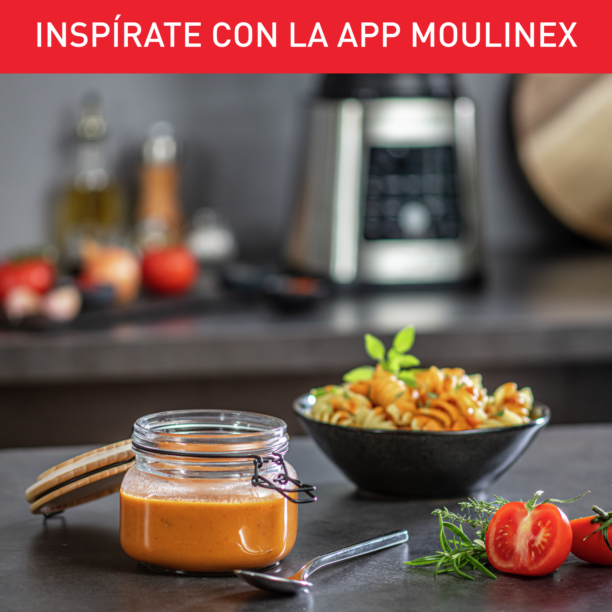 Un tarro de salsa naranja con tomates y hierbas está sobre una mesa. Pasta en un cuenco negro.