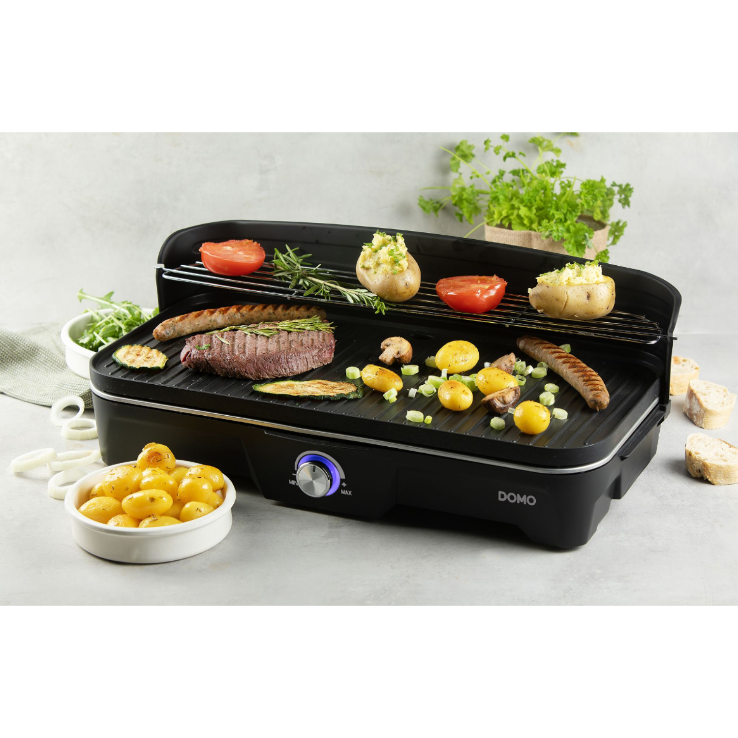 Een zwarte grill met eten, waaronder tomaten en worstjes.