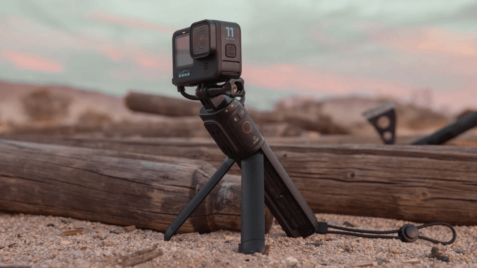 Cámara GoPro en un mini trípode en un paisaje desértico con troncos de madera.