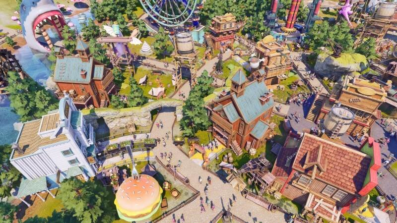 Widok z lotu ptaka na park rozrywki z przejażdżkami, budynkami, ludźmi.