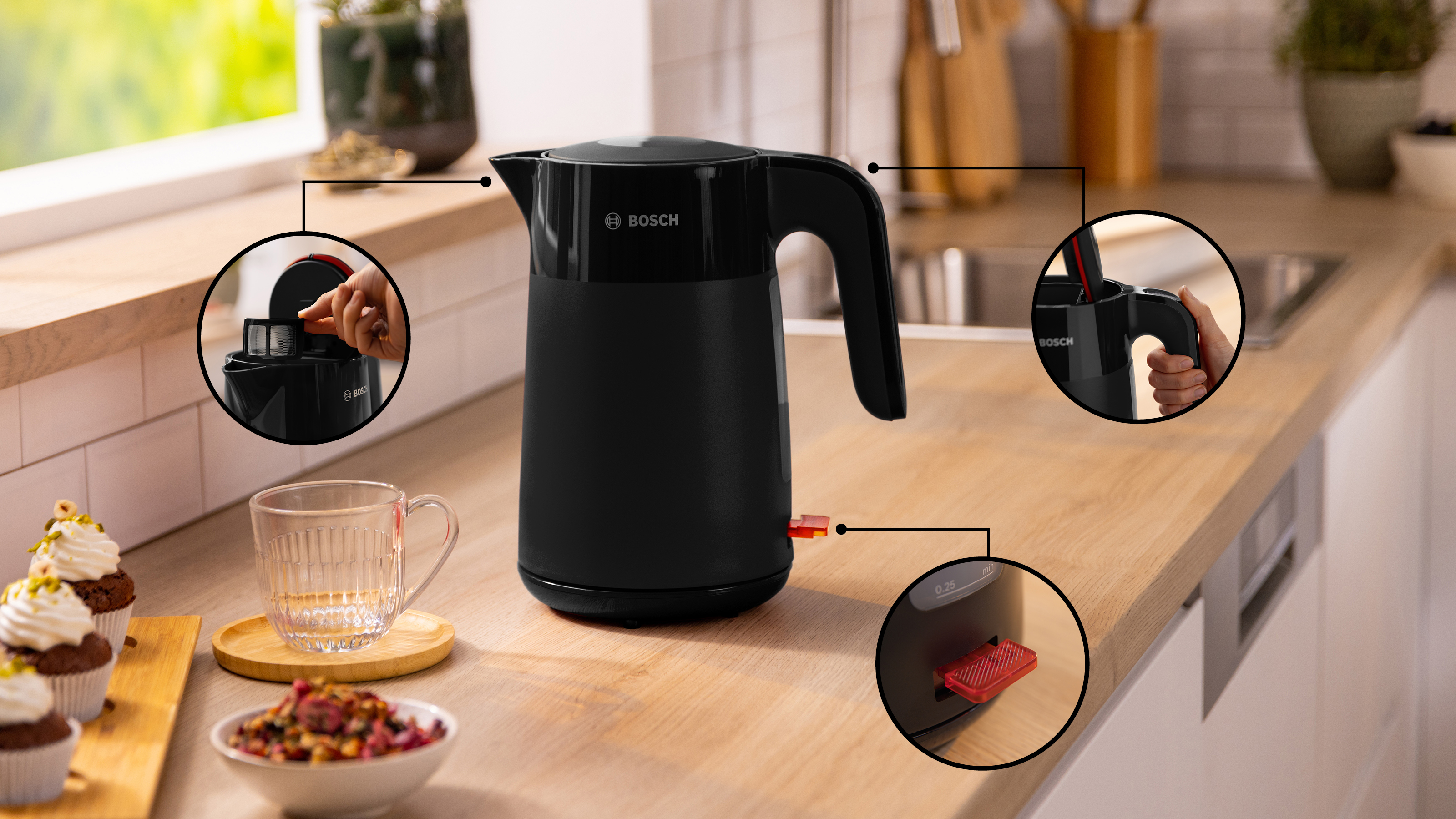 Schwarzer Wasserkocher mit Nahaufnahmen, auf Holzoberfläche, neben Tasse und Gebäck.