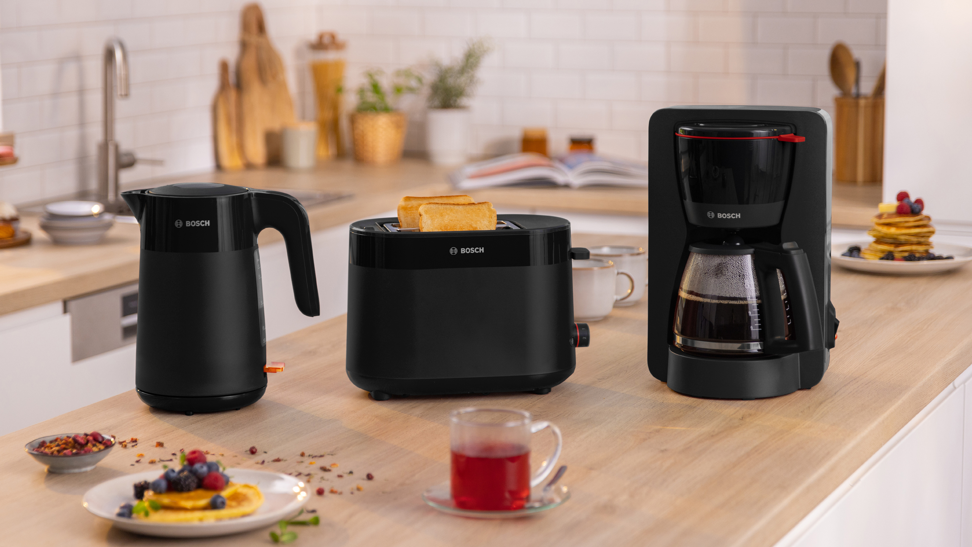 Ein Frühstücksaufbau mit Wasserkocher, Toaster und Kaffeemaschine auf einer Theke.