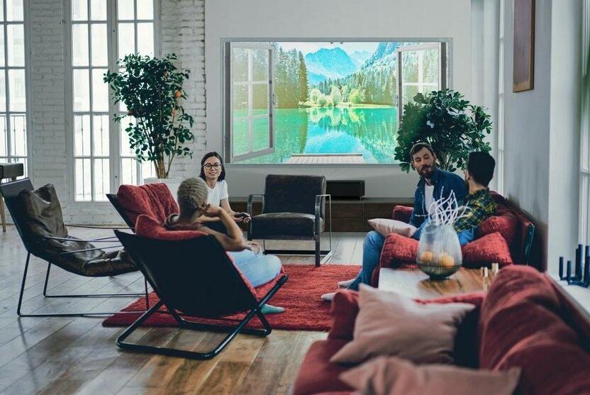 Ludzie oglądający duży ekran telewizora wyświetlający krajobraz, w przytulnym salonie.