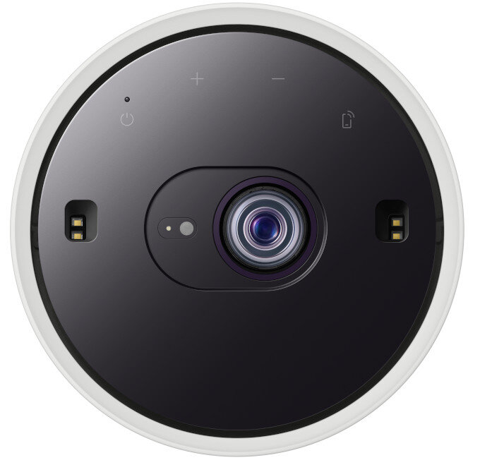 Czarny projektor z białą obwódką. Widok z góry pokazujący obiektyw i elementy sterujące.