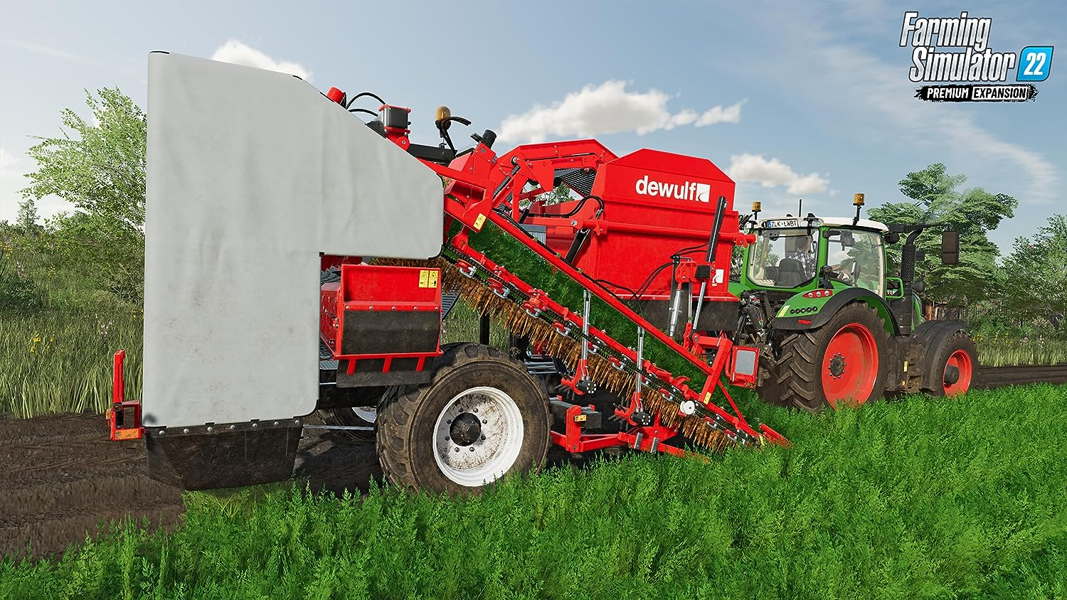 Máquina agrícola roja y plateada cortando hierba en un campo con un tractor verde. Cielo azul al fondo.