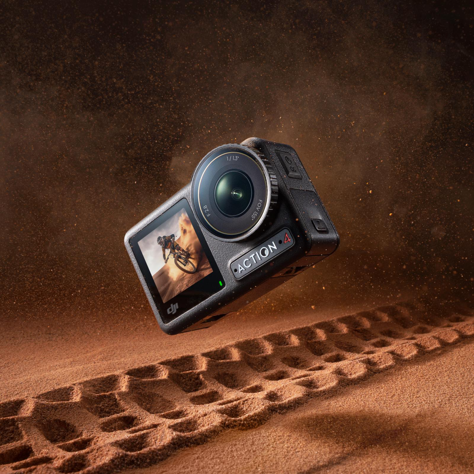 Schwarze DJI Action 4 Kamera in der Luft, mit Sand im Hintergrund.