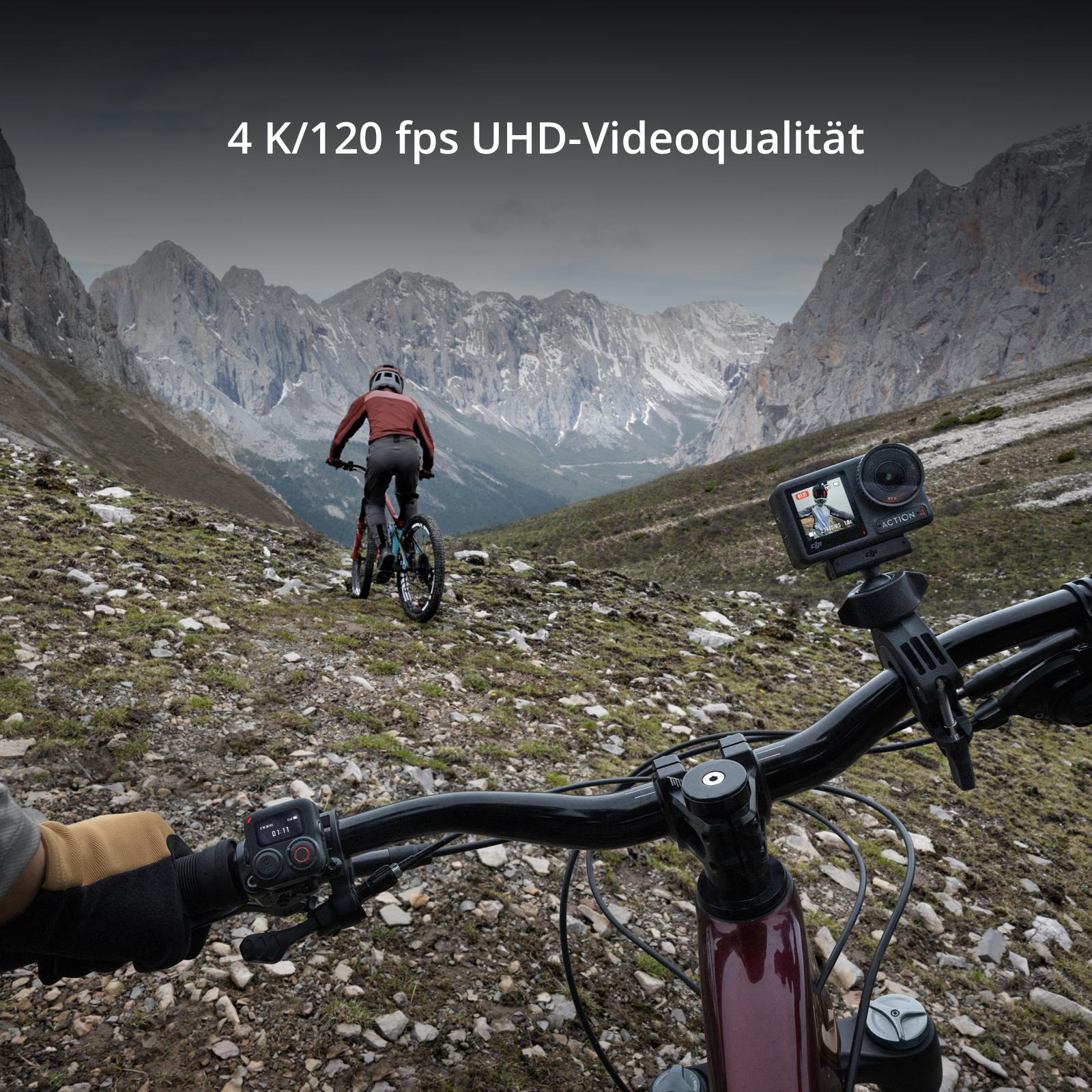Eine Person auf einem Mountainbike, mit einer Kamera am Lenker, in einer Berglandschaft.