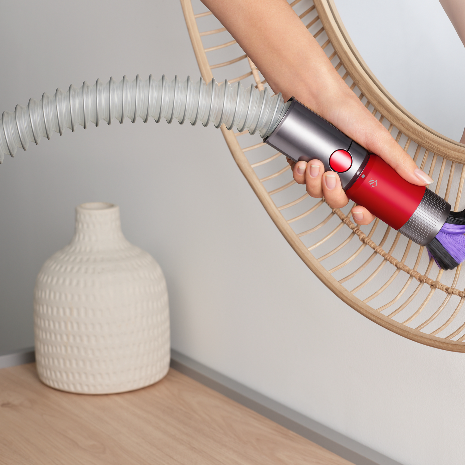 Een vrouw gebruikt een rode en zilveren stofzuiger met de kop op de spiegel.
