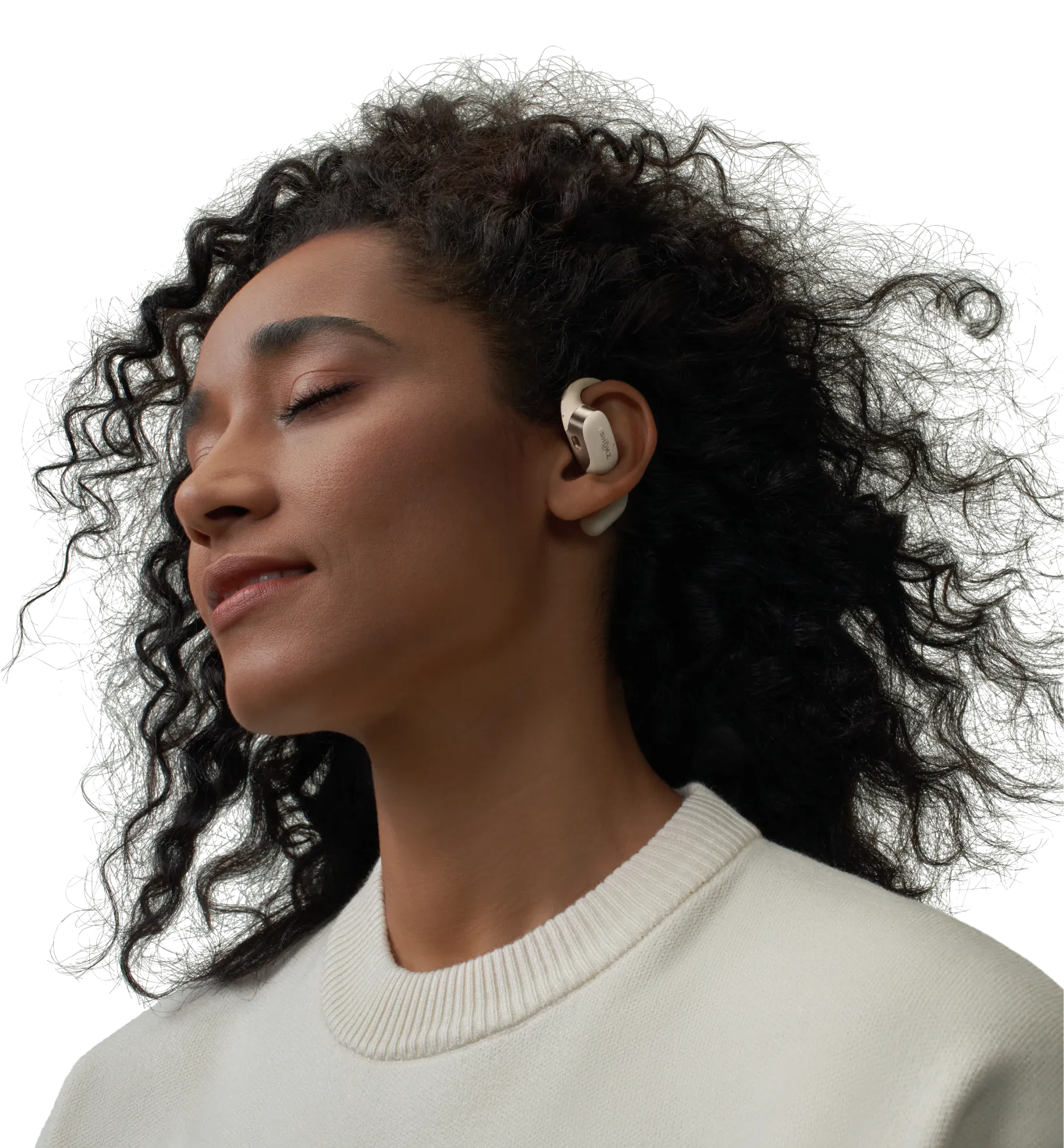 Femme avec écouteur dans l'oreille, portant un pull blanc, les yeux fermés.
