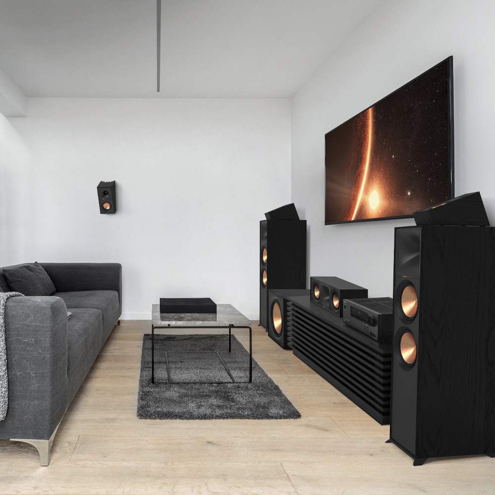 Living room with speakers, TV, and a sofa. The TV shows a space image.