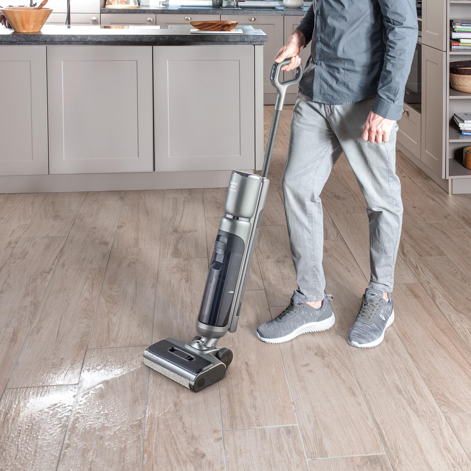 Eine Person reinigt einen Holzboden mit einer silbernen und schwarzen Bodenreinigungsmaschine.
