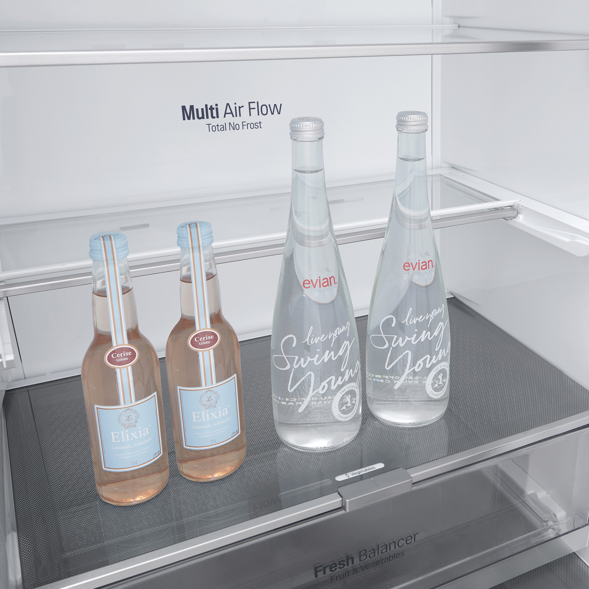 Dentro de un refrigerador. Botellas de agua y refresco rosa están en la puerta y en un estante.