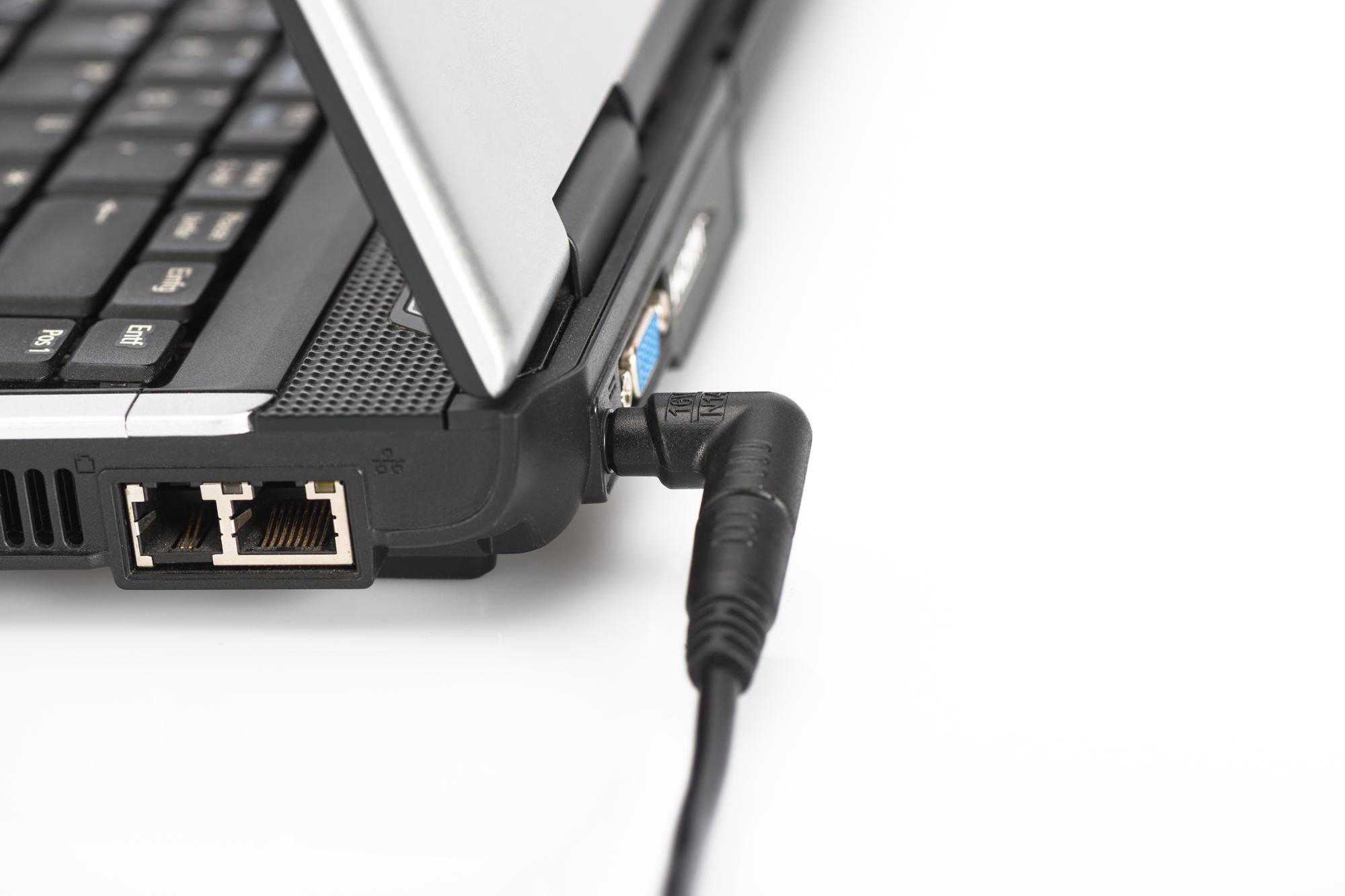 Laptop mit eingestecktem Netzkabel, weißer Hintergrund.