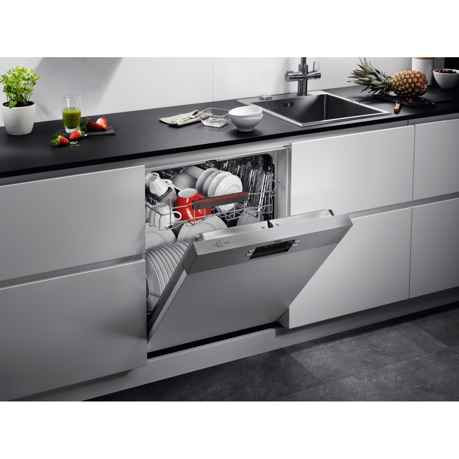 Lave-vaisselle avec la porte ouverte, montrant de la vaisselle propre et une tasse rouge à l'intérieur, dans une cuisine.
