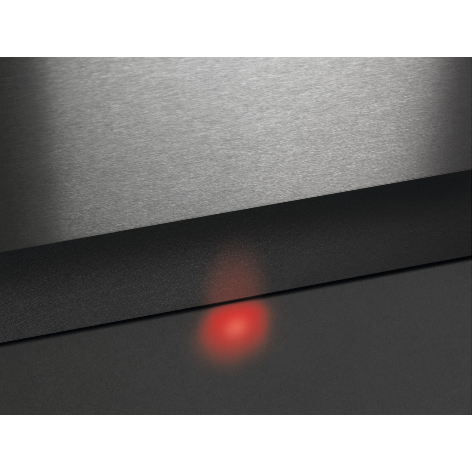 Gros plan d'une base noire avec une lumière rouge et une surface métallique argentée.