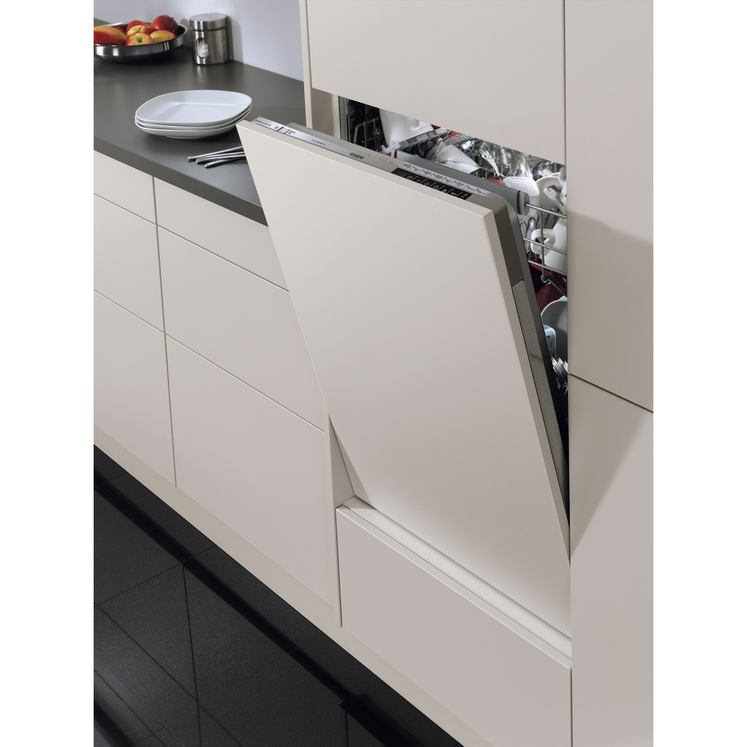 Porte du lave-vaisselle ouverte. Vaisselle à l'intérieur. Comptoir et armoires de cuisine en arrière-plan.