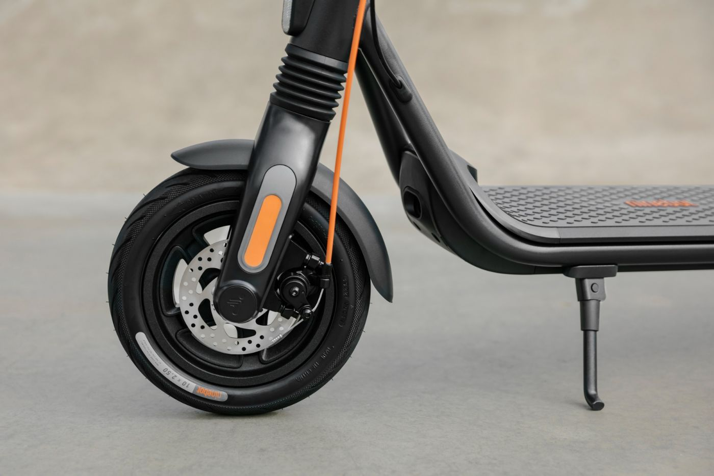 Schwarzer und grauer Roller mit orangefarbenem Kabel und Nahaufnahme des Rads.