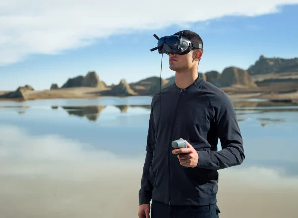 Mężczyzna w zestawie VR w krajobrazie pustynnym. Błękitne niebo, woda odbija niebo.