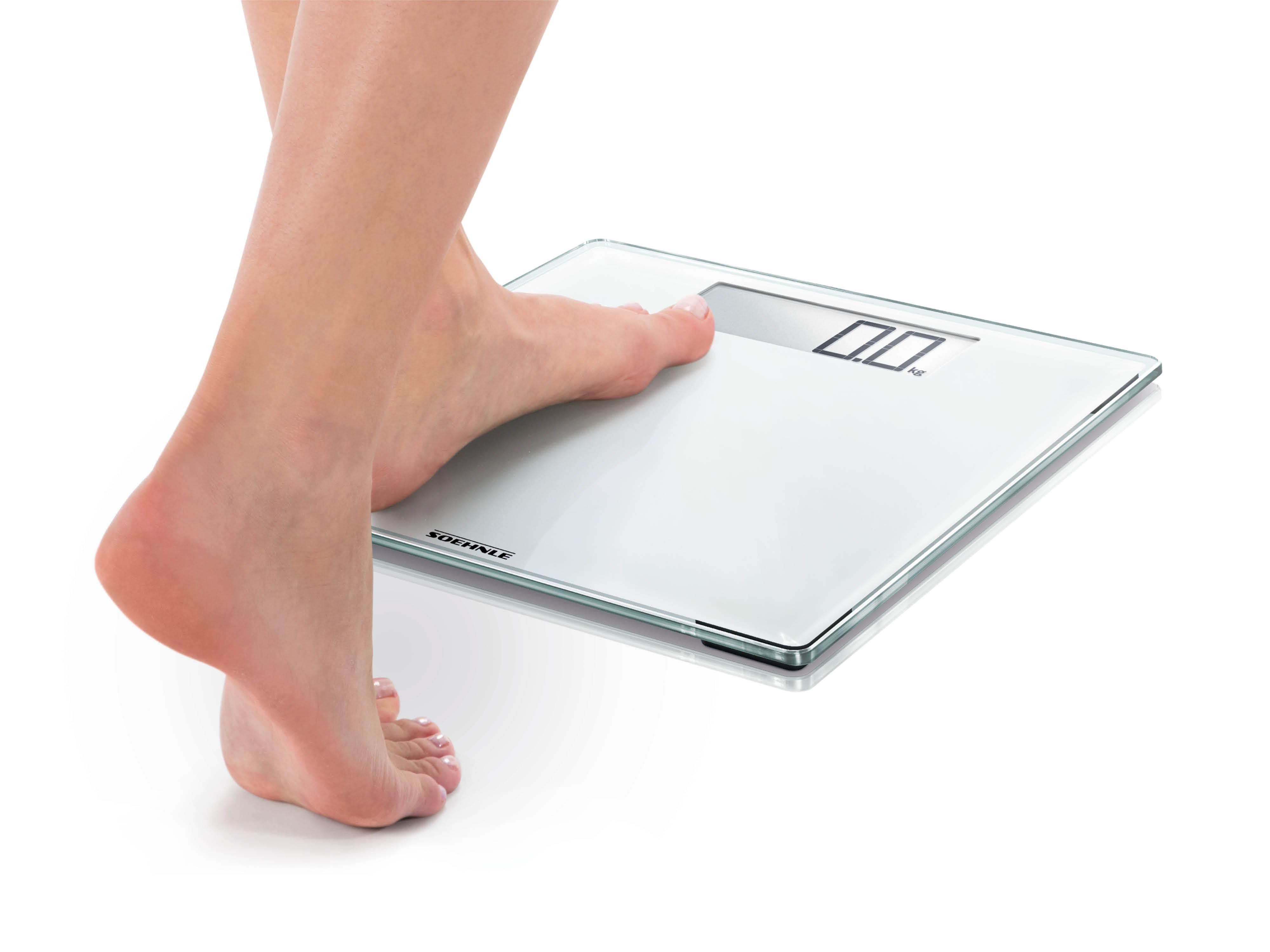 Eine Person steht auf einer weißen Waage. Die Waage zeigt 0,0 kg an.