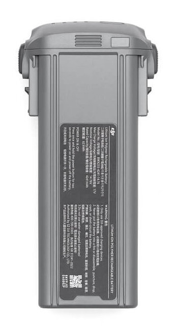 Szary prostokątny akumulator z etykietami i tekstem, widok z góry, białe tło.