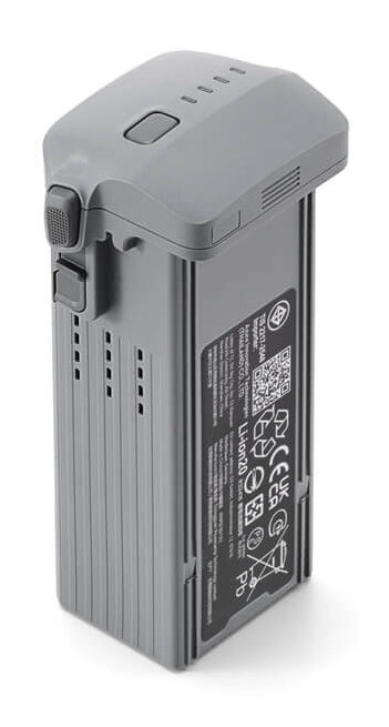 Szara bateria do drona na białym tle. Posiada kilka etykiet bezpieczeństwa i przycisk.