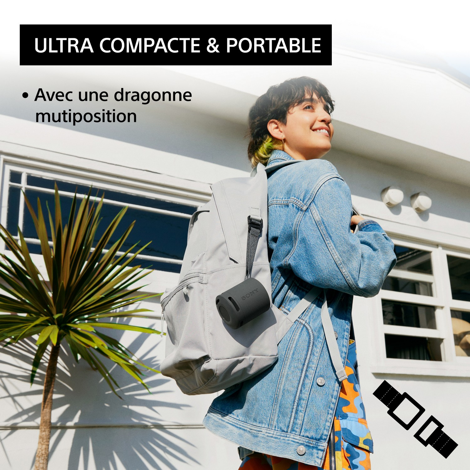 Femme avec un sac à dos portant une veste en jean avec un haut-parleur portable attaché au sac.