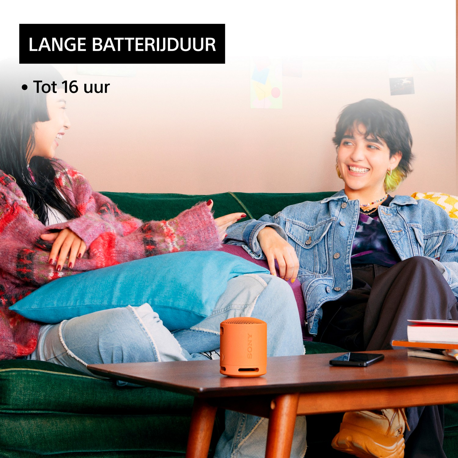Twee vrouwen met een kleine oranje luidspreker, zittend op een bank.