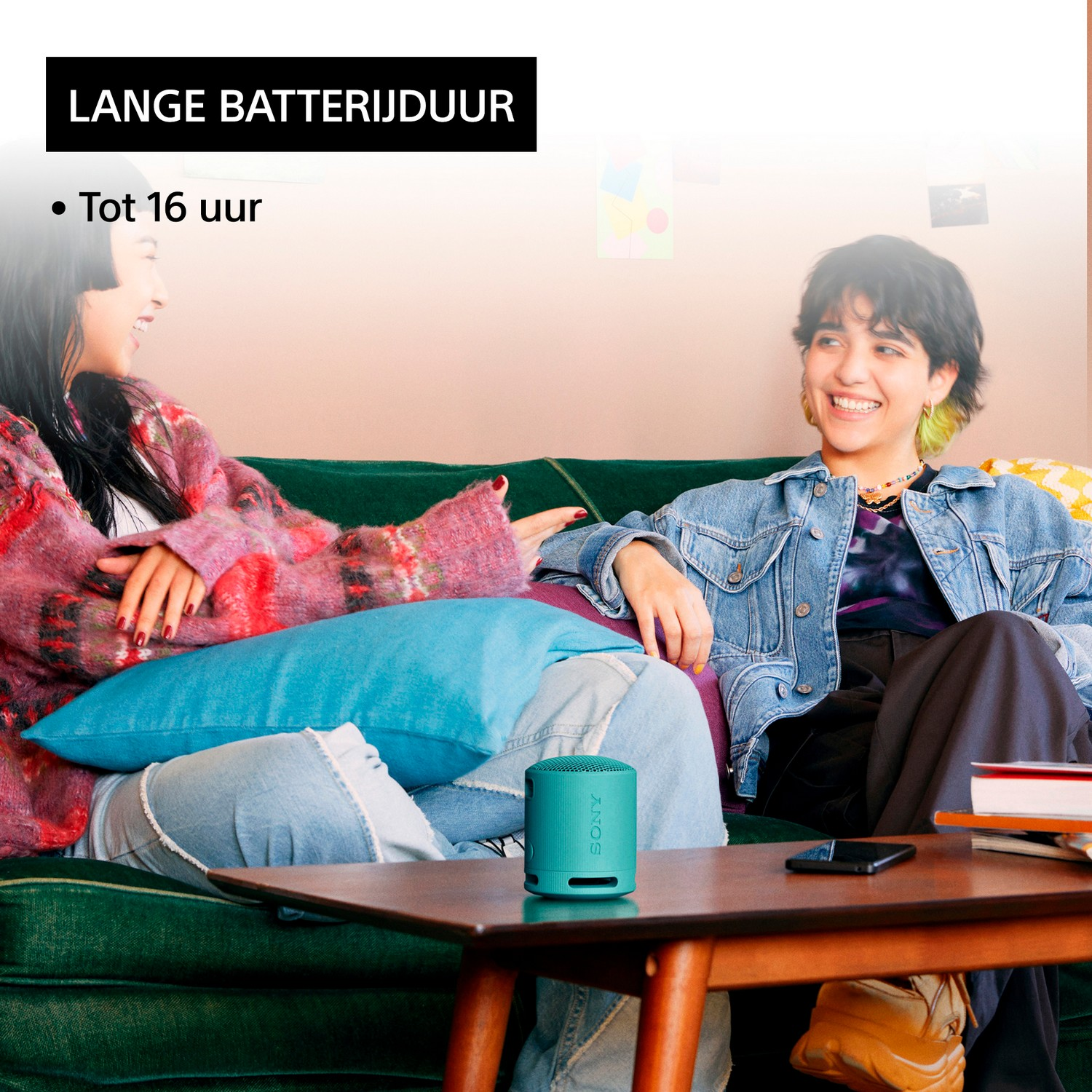 Twee vrouwen, een houdt een luidspreker vast, lachen en praten.